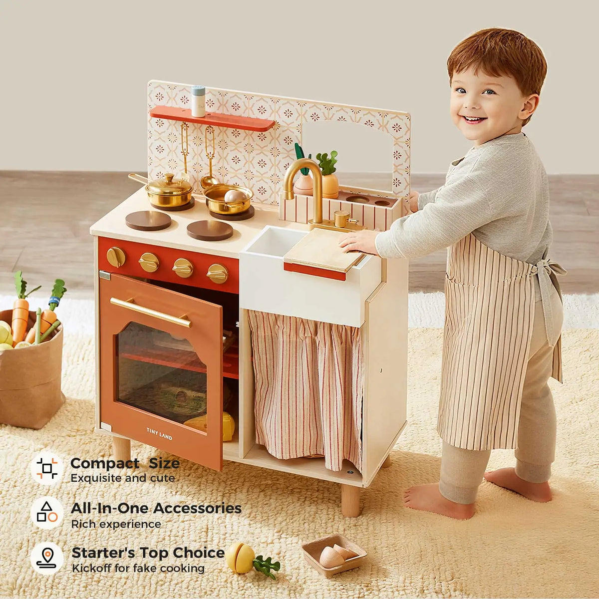A young child smiles in a cozy room while playing with the Tiny Land® Mediterranean Play Kitchen by Tiny Land INC, featuring wooden pots, utensils, an oven, and a sink. Text highlights this educational toy kitchen's features.