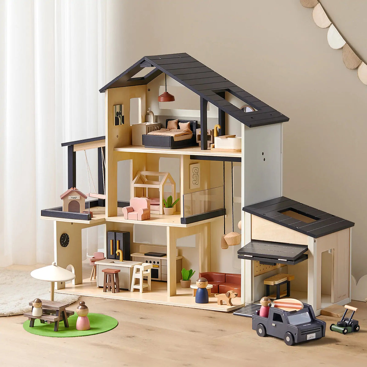 The Tiny Land® Sweetwood Edge Dollhouse & Wooden Dollhouse Garage features multiple rooms, cozy furniture, a wooden garage with a small toy car, kitchen, bedroom, living area, and a picnic table with umbrella in front.
