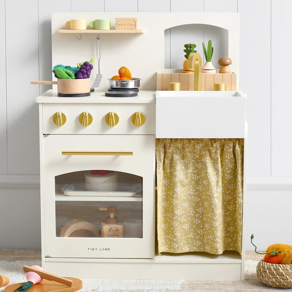 The Tiny Land® Wooden Play Kitchen for Toddlers - Honey Kitchenette features a stove, oven, sink with yellow floral curtain, shelves with toy food and utensils, plus play veggies—ideal for imaginative play.